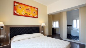 A hotel room with a large bed, a headboard, two bedside lamps, and a painting on the wall. - Hotel Ferton (Milan)
