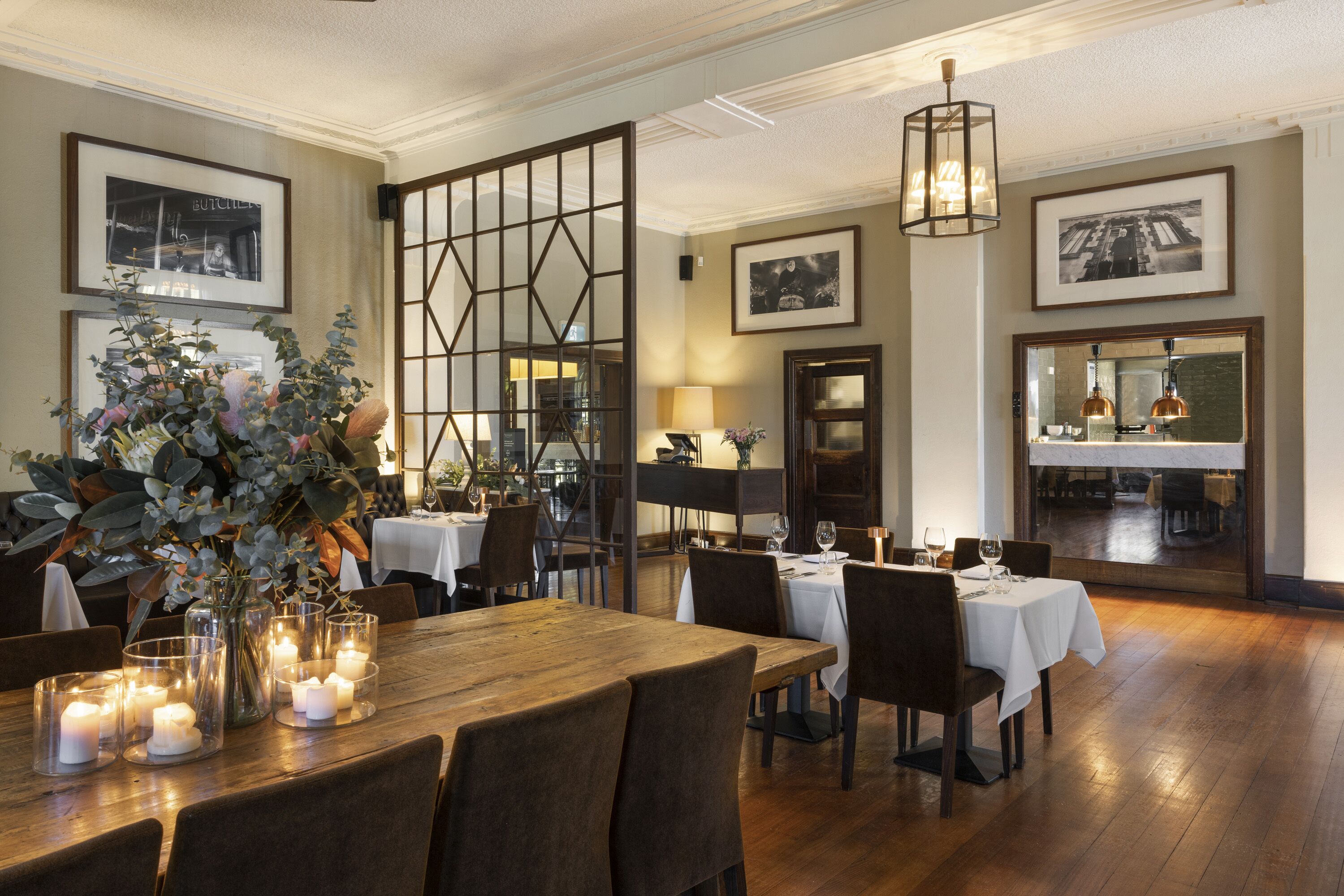 A dining area with wooden tables, chairs, and candle-lit centerpieces.