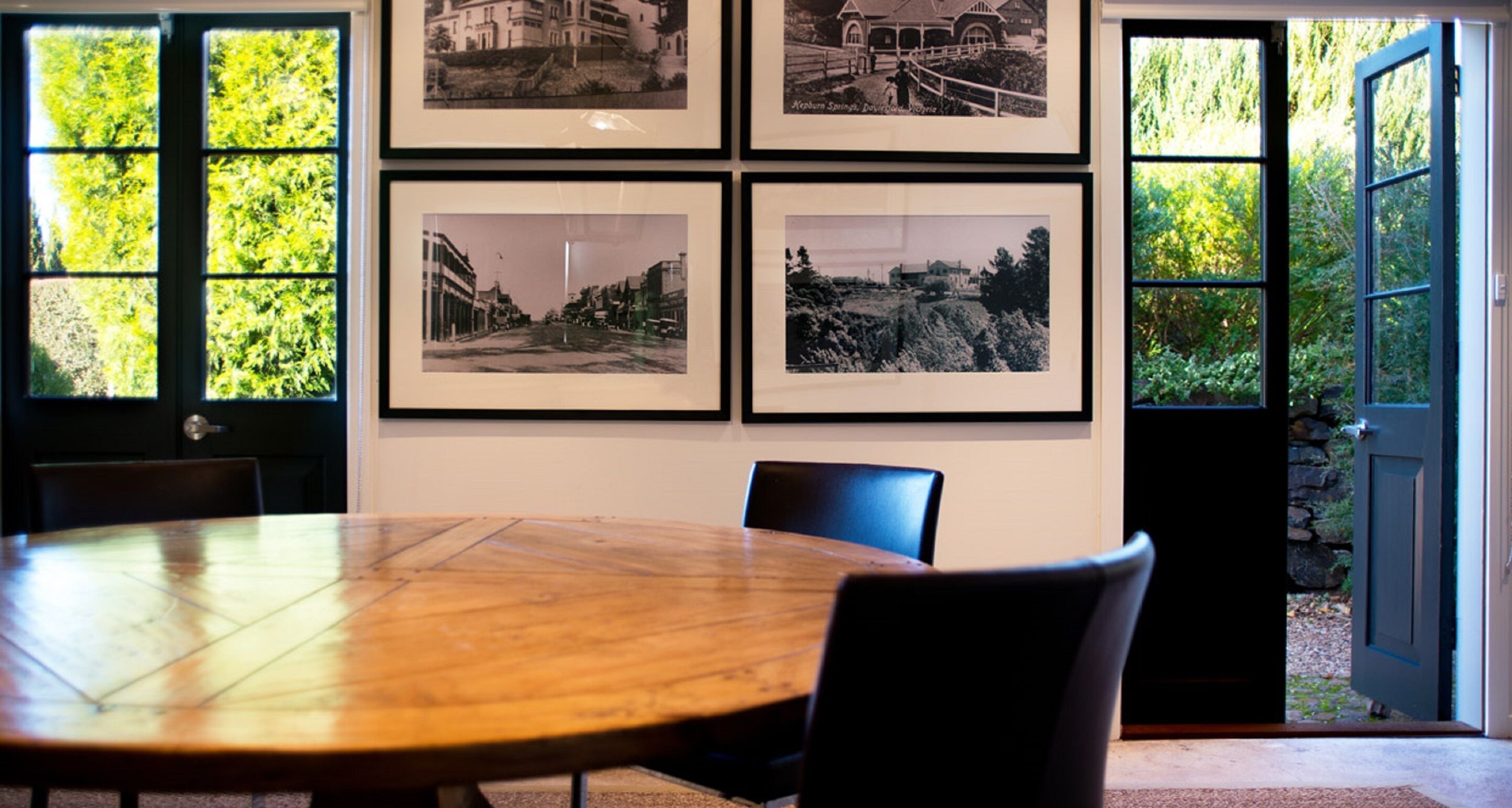 A conference room with a wooden table, four chairs, and four framed black and white photographs on the wall.