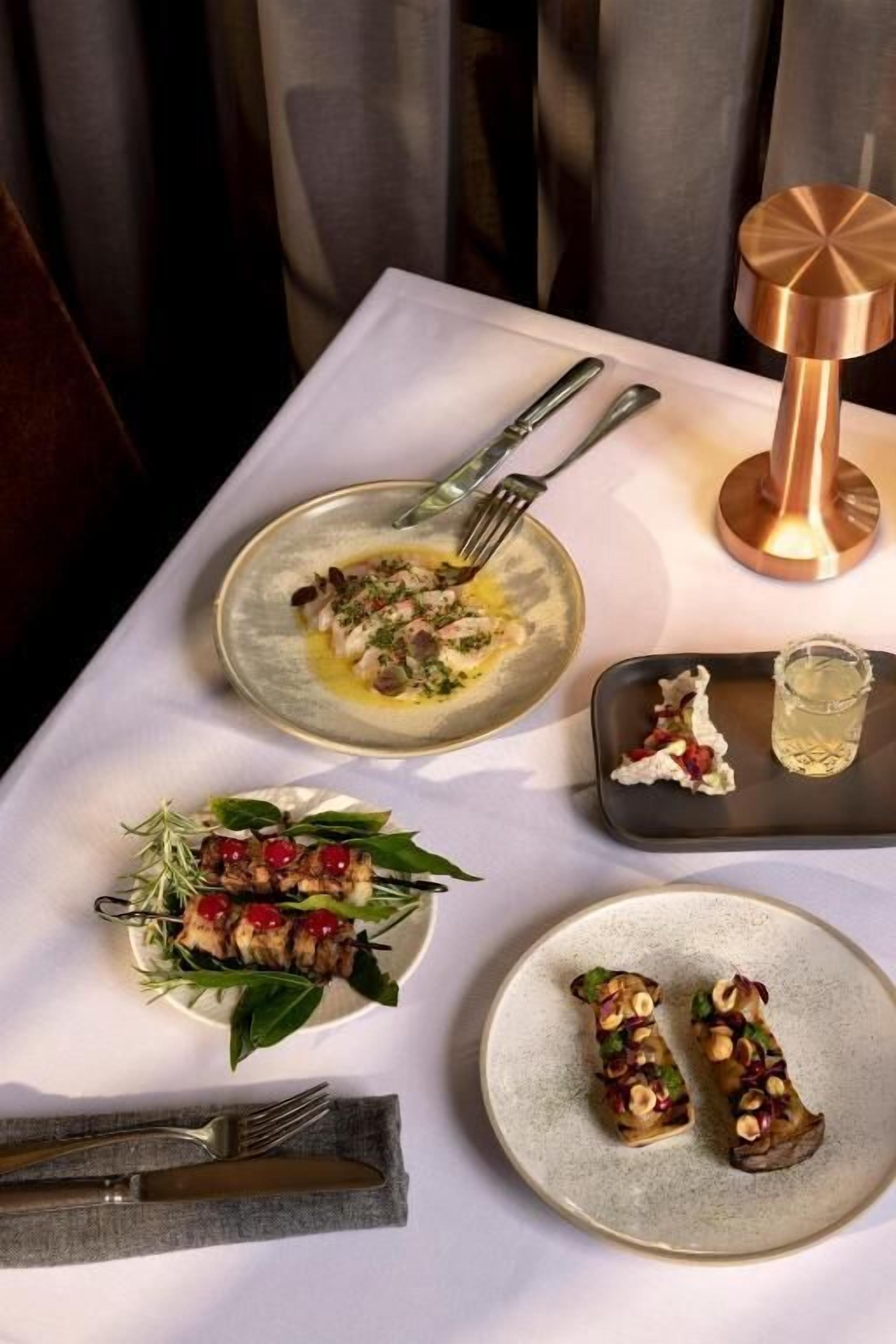 A dining table with various dishes, cutlery, and a candle.