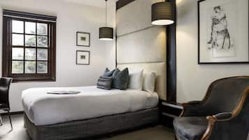 Un dormitorio moderno con una cama grande, una mesita de noche, una silla y una ventana con cuadros.