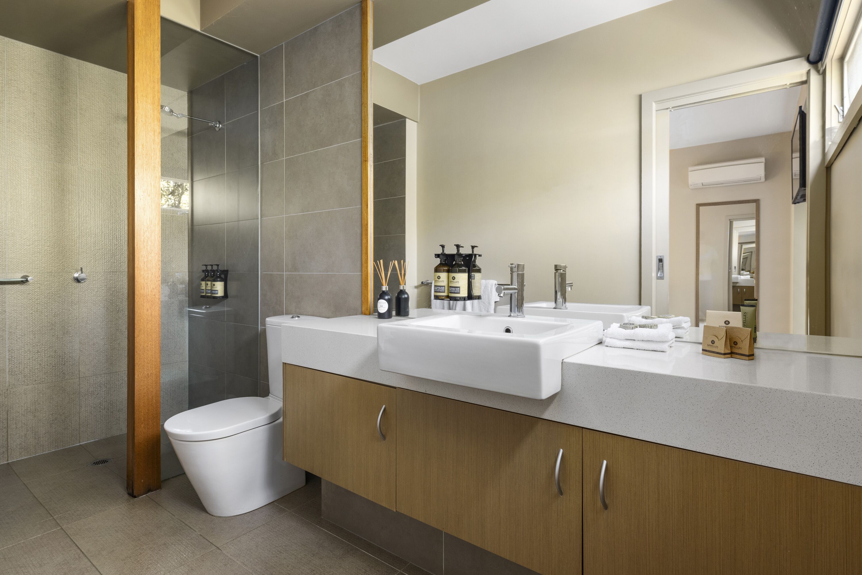 A modern bathroom with a shower, two sinks, and a toilet.