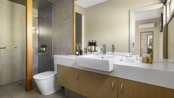 A modern bathroom with a shower, two sinks, and a toilet.