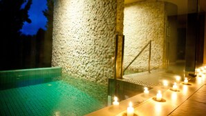 A stone wall and a pool area with candles. - Mineral Springs Hotel (Hepburn Springs)