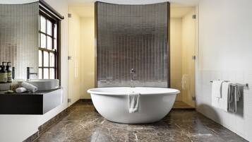Un baño moderno con una bañera independiente, un lavamanos empotrado y un espejo grande.