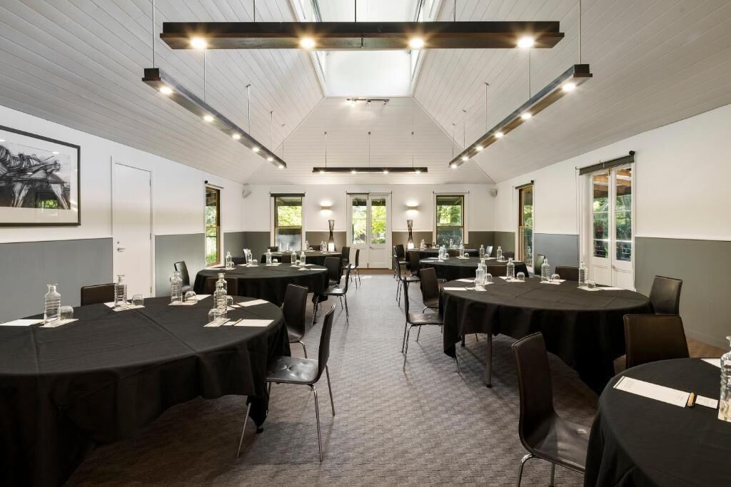 A conference room with multiple tables, chairs, and a high ceiling with skylights.