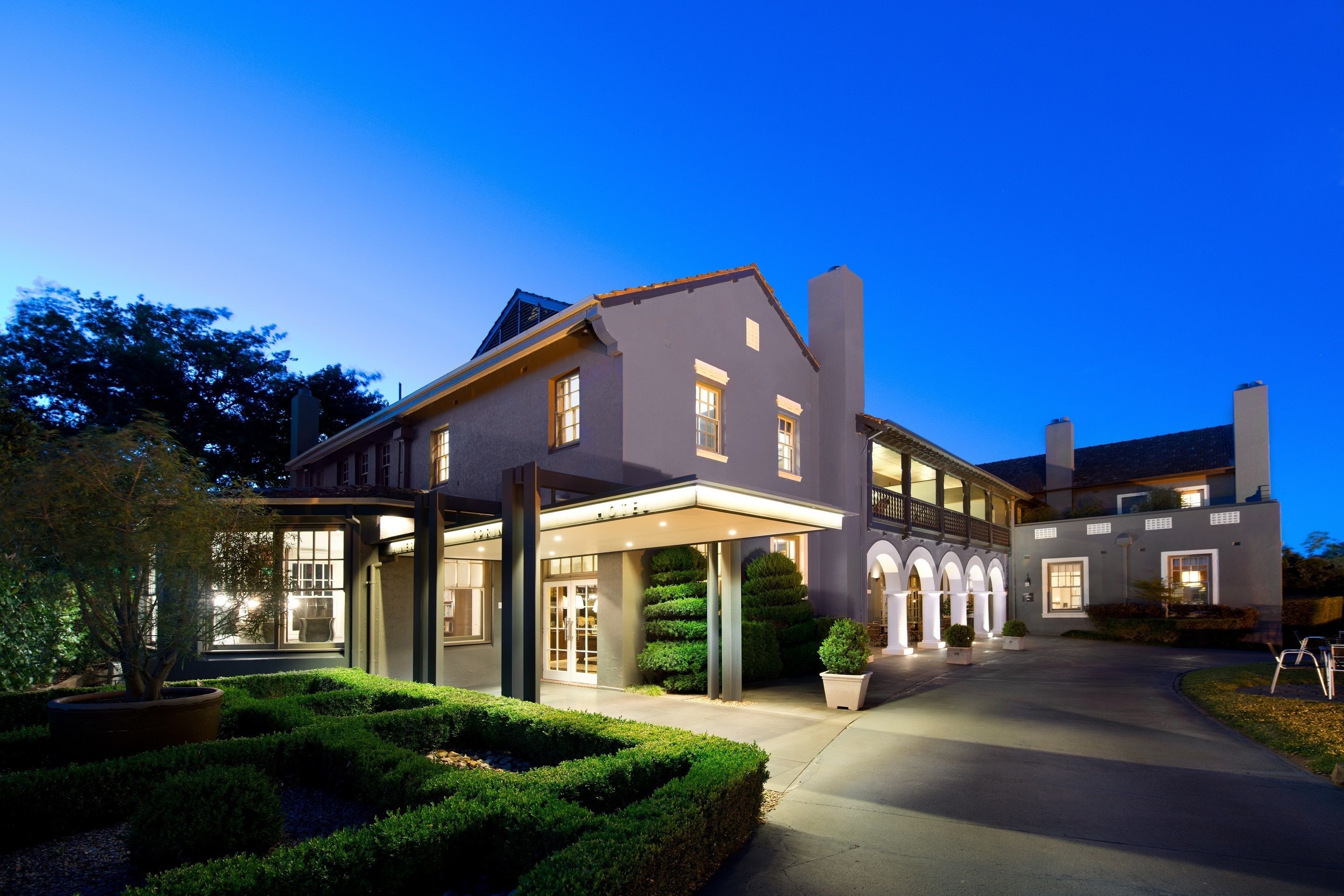 A large, modern hotel with a covered entrance, multiple windows, and a well-maintained garden.