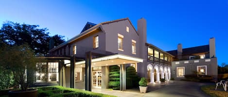 A large, modern hotel with a covered entrance, multiple windows, and a well-maintained garden.