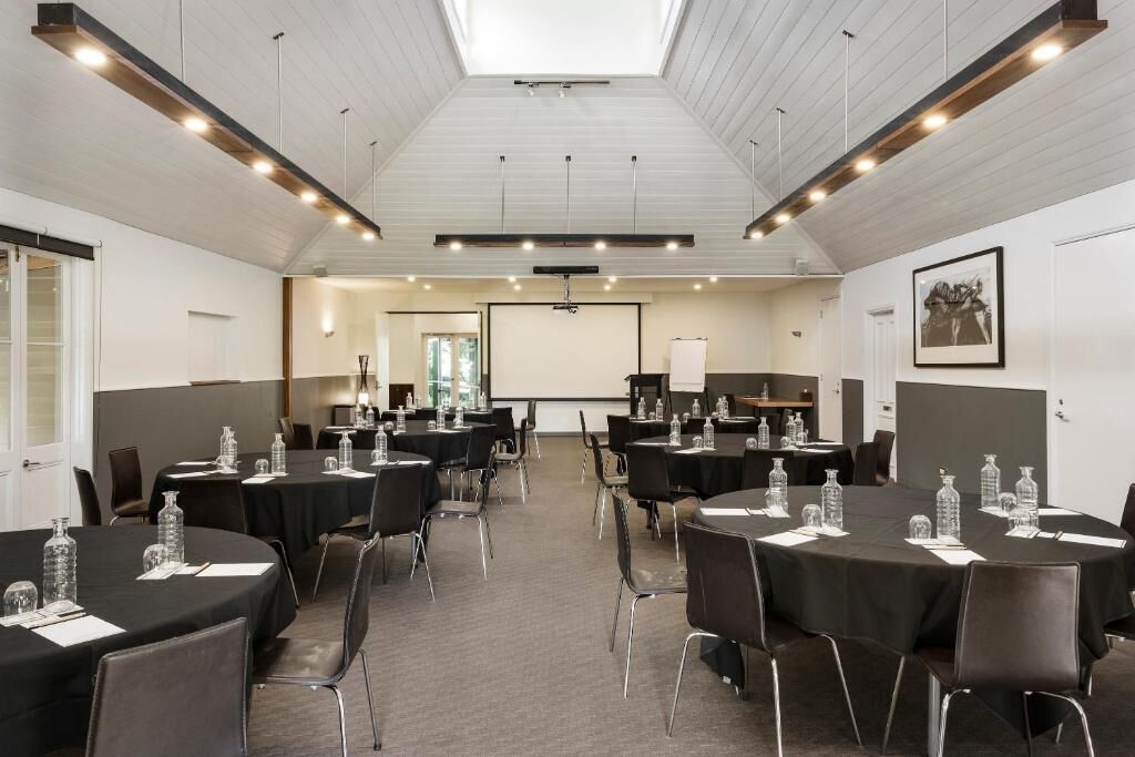 A conference room with round tables, chairs, and water bottles.