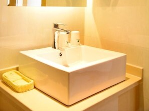 Un baño con un lavabo blanco, un espejo y un perchero para toallas.