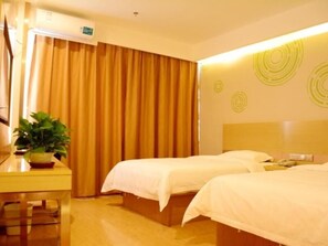 Habitación de hotel con dos camas, un escritorio con una planta, una cortina y una pared con diseños circulares.