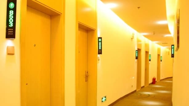 Un pasillo de hotel con puertas numeradas y señales de indicaciones.