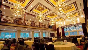 A banquet hall with round tables, chandeliers, and a balcony with railings. - Grand Hotel Yuanshan (Beijing)