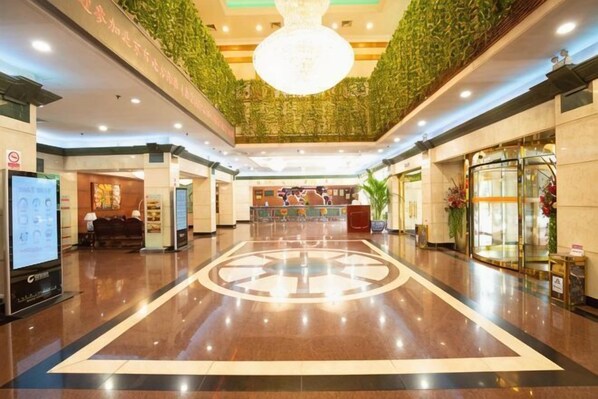 A hotel lobby with a polished floor, a reception desk, a large chandelier, and a green wall. - Grand Hotel Yuanshan (Beijing)