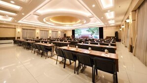 A conference room with rows of tables and chairs, a large screen at the front, and a modern ceiling design. - Grand Hotel Yuanshan (Beijing)