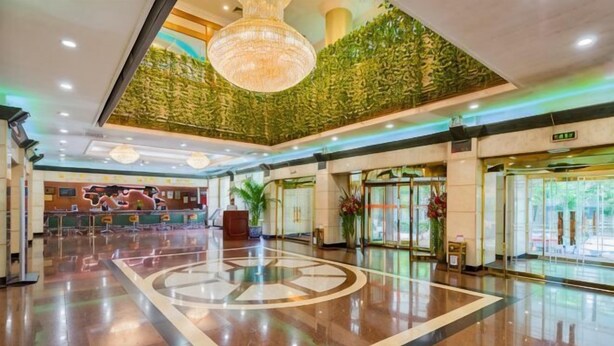 A spacious lobby with a central circular design, a reception desk, and a green wall. - Grand Hotel Yuanshan (Beijing)
