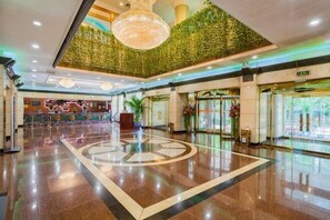 Un vestíbulo amplio con un diseño circular central, una recepción y una pared verde.