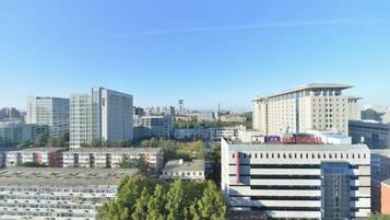 A cityscape with various buildings, including a large multi-story structure with a flat roof and a smaller building with a sloped roof.