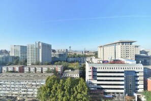 A cityscape with various buildings, including a large multi-story structure with a flat roof and a smaller building with a sloped roof. - Grand Hotel Yuanshan (Beijing)