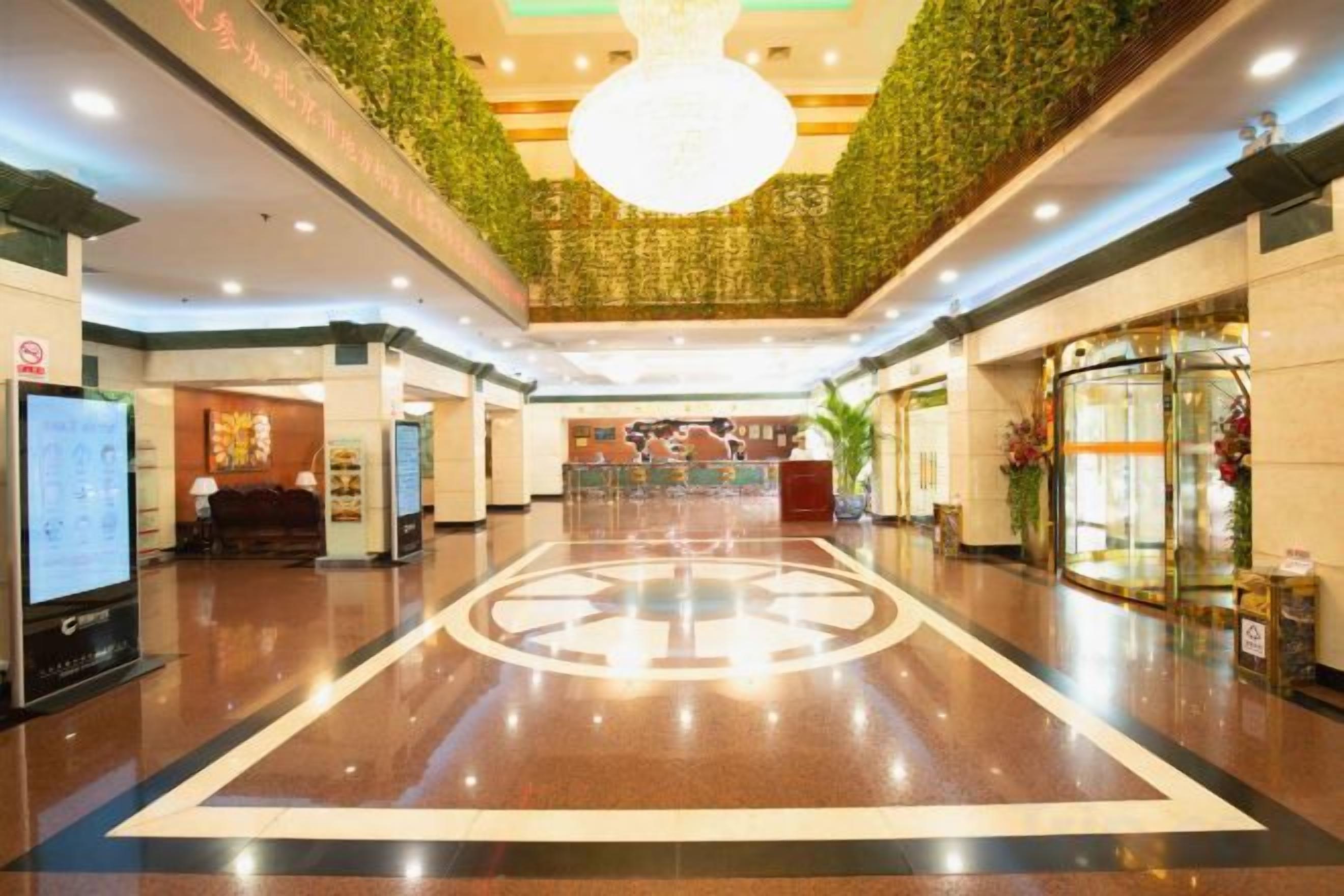 A hotel lobby with a reception desk, a digital information kiosk, and a decorative ceiling.