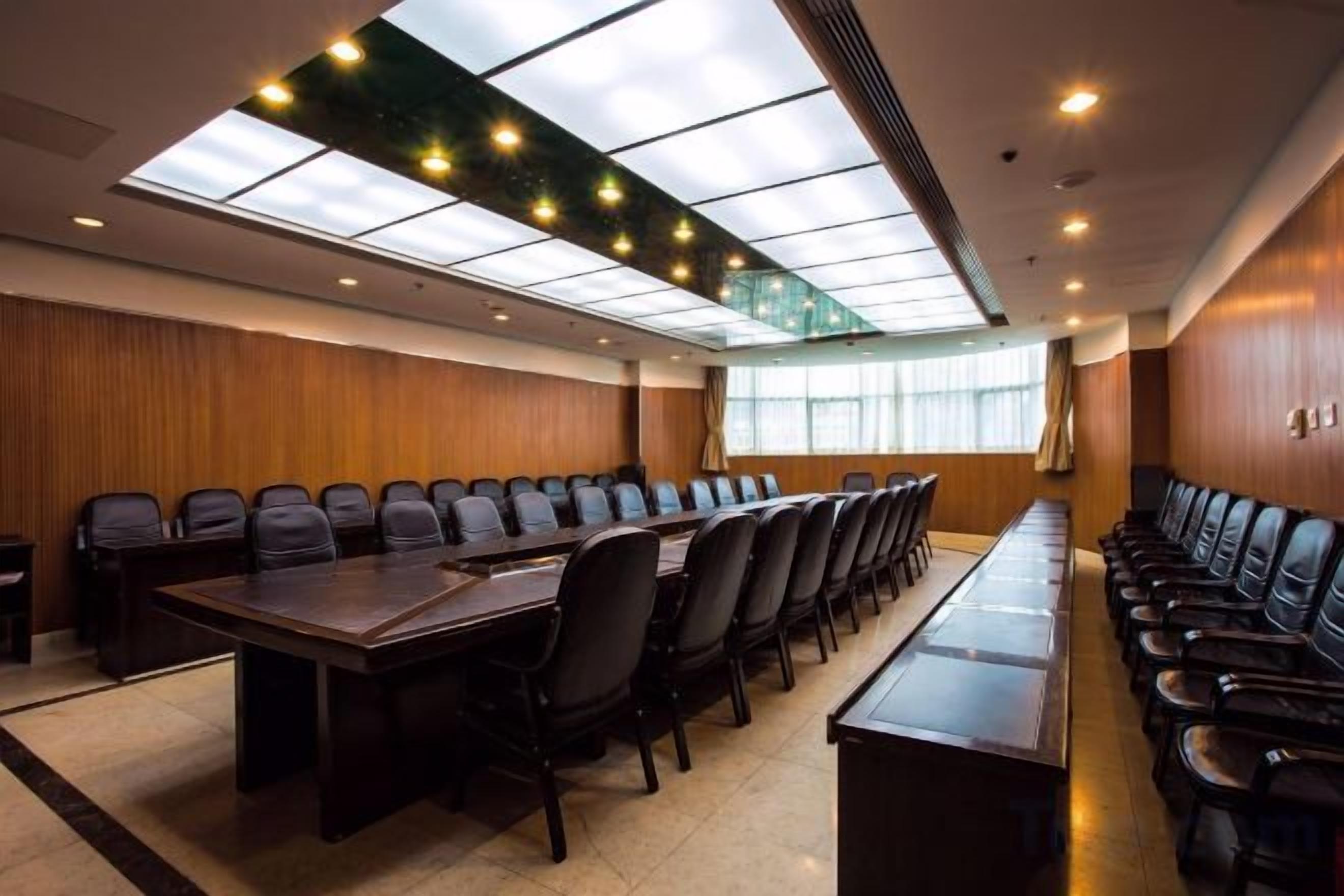 A conference room with a long table, multiple chairs, and a high ceiling with skylights.