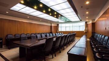 A conference room with a long table, multiple chairs, and a high ceiling with skylights.