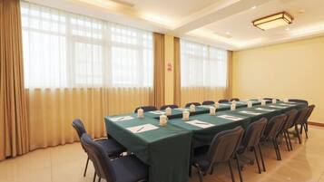 A conference room with a long table, chairs, and a window with curtains.