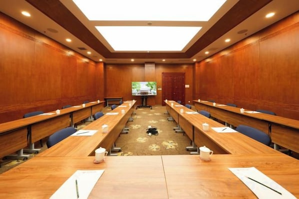 A conference room with long tables, chairs, and a large screen at the front. - Grand Hotel Yuanshan (Beijing)