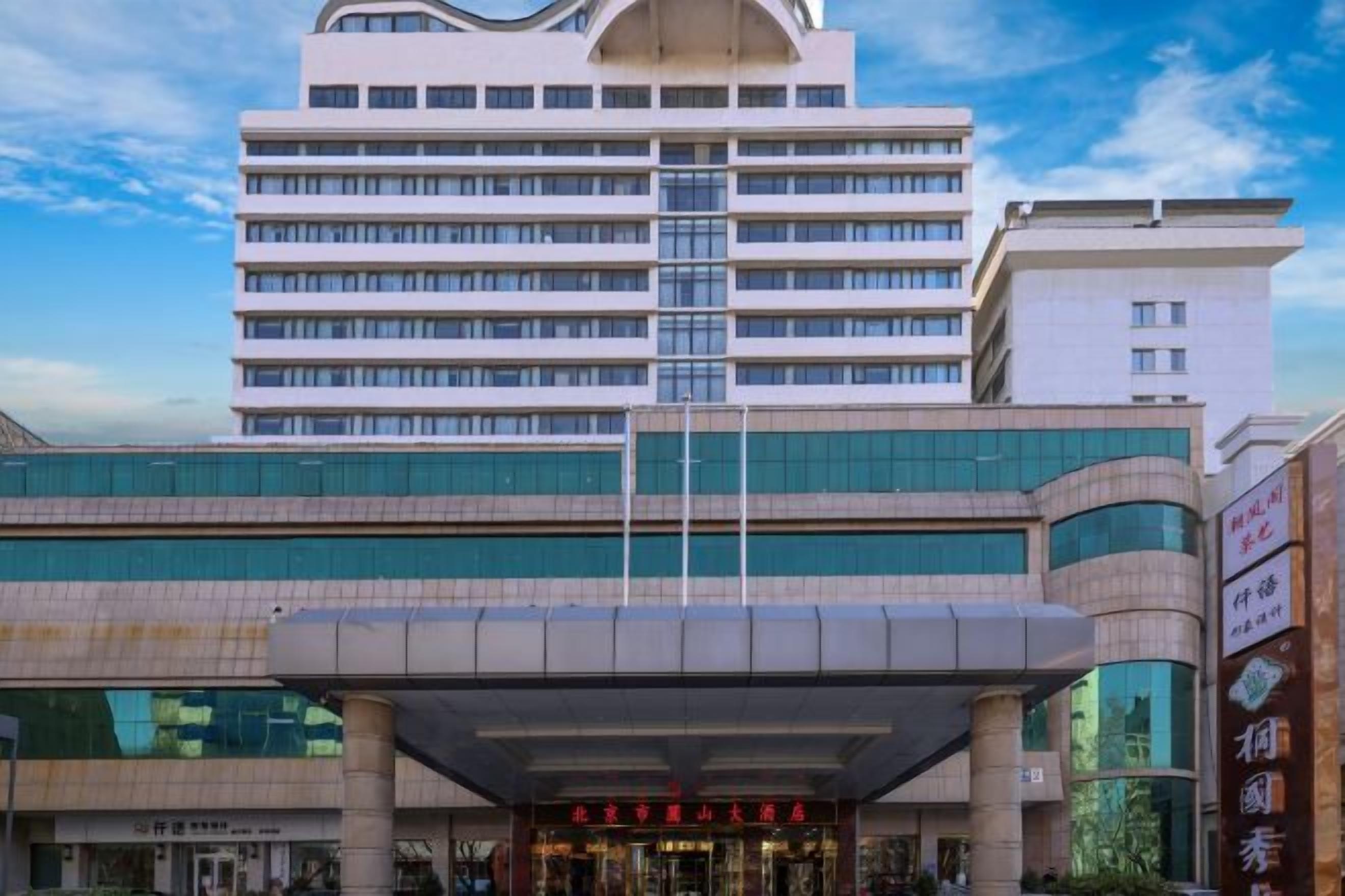 Un hôtel à plusieurs étages au design moderne, doté d’une entrée imposante et d’une allée couverte.