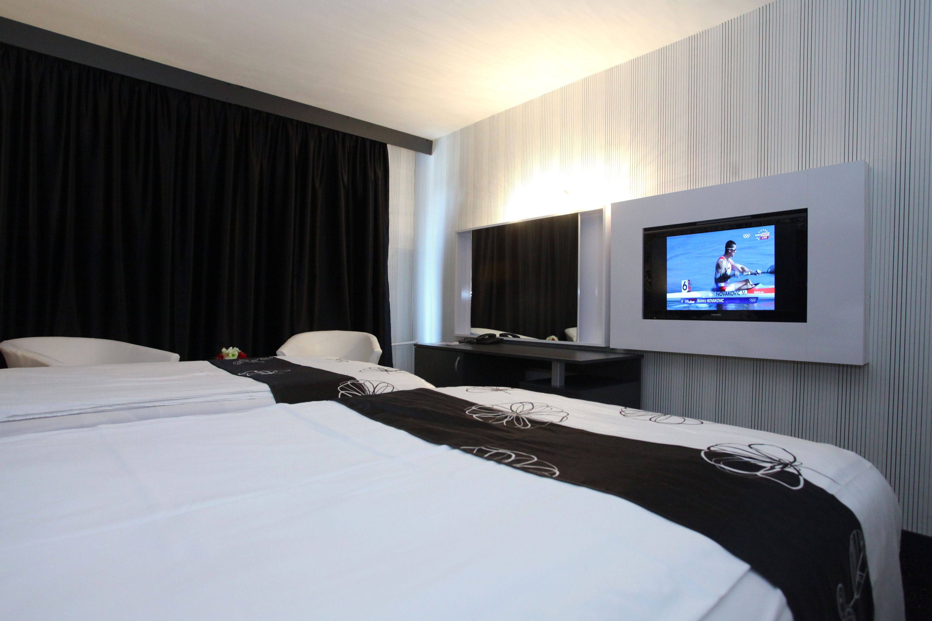 Une chambre d’hôtel avec deux lits, un téléviseur fixé au mur, un bureau et une chaise.
