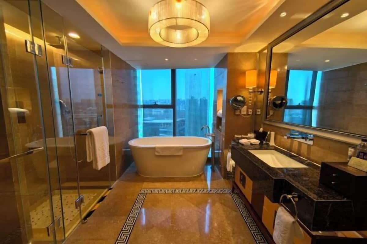 Ein modernes Badezimmer mit einer freistehenden Badewanne, einer in Glas abgeschirmten Dusche, einem großen Spiegel und einem Waschtisch mit Spüle.