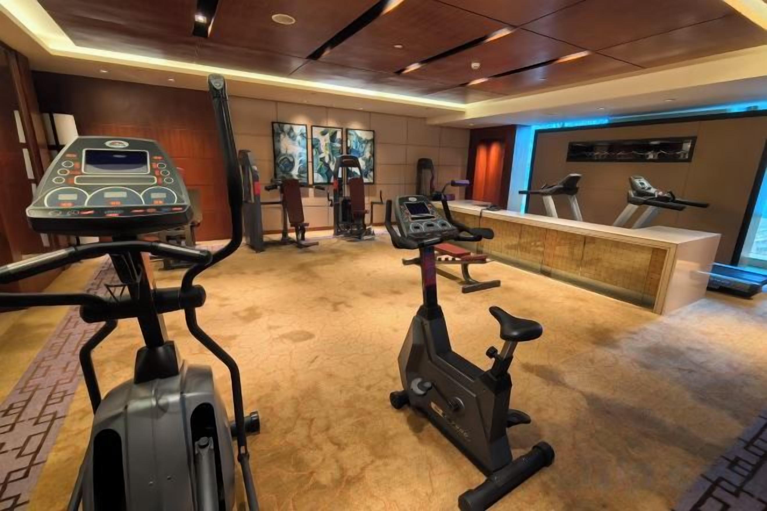 A gym with cardio machines, a weight bench, and a reception desk.
