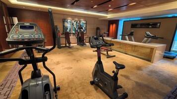 A gym with cardio machines, a weight bench, and a reception desk.
