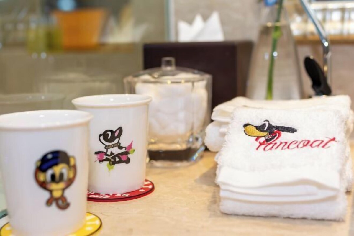 A table with a mug, a candle, and a towel with a cartoon character.