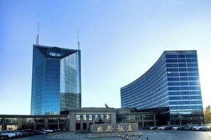 Un edificio moderno con una entrada amplia y un área de estacionamiento.