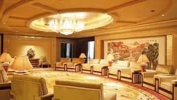 Un hall de hotel con una zona de estar circular, una araña y un cuadro grande en la pared.