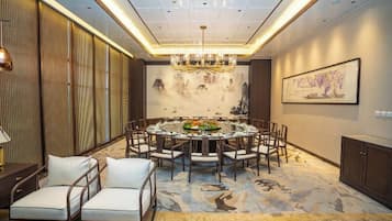 A dining area with a round table, chairs, and a chandelier.