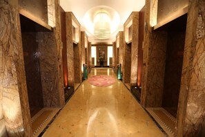 A marble-floored corridor with a red carpet, leading to a reception area with a chandelier. - International Hotel (Langfang)