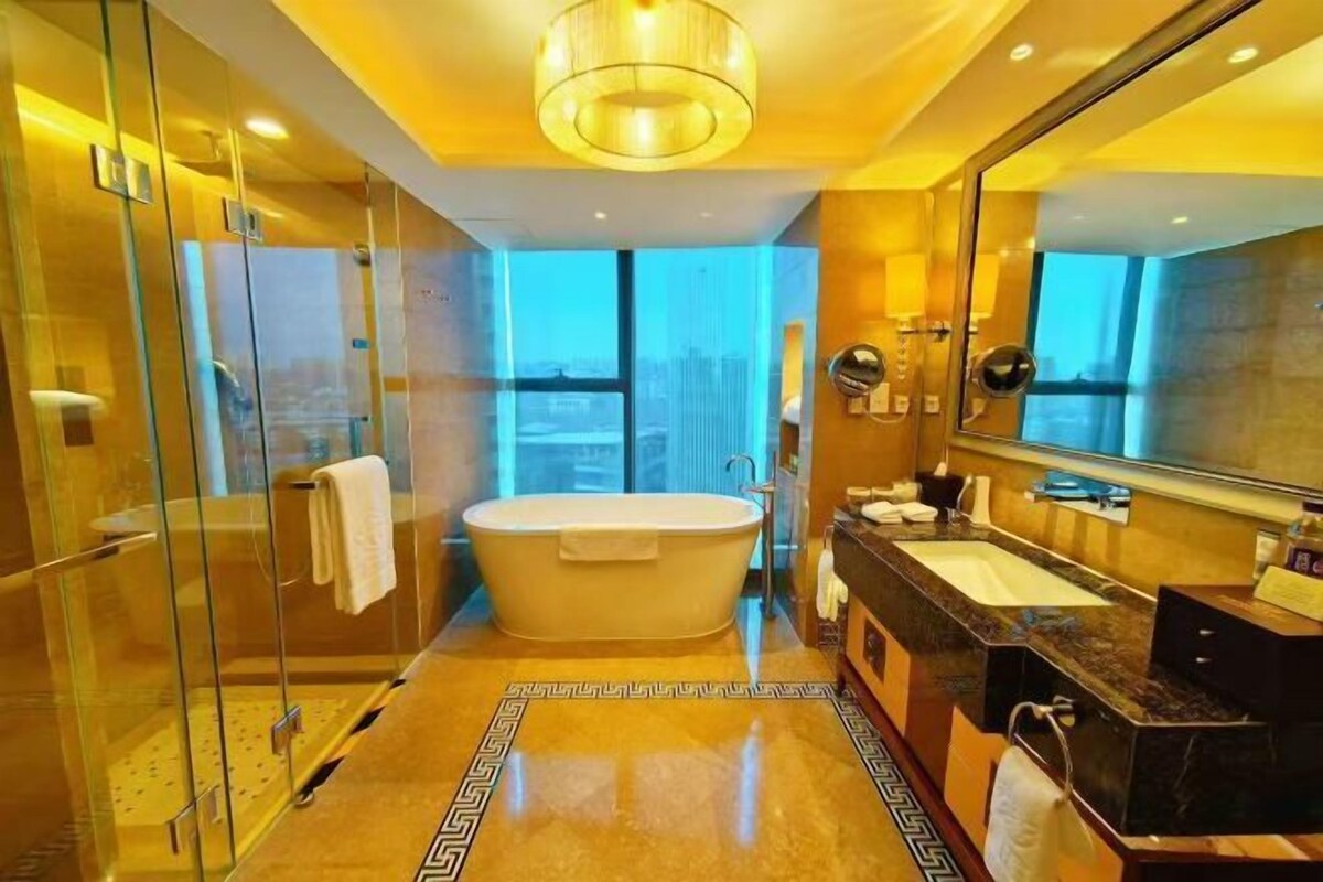 A modern bathroom with a glass-enclosed shower, a freestanding bathtub, and a large mirror.