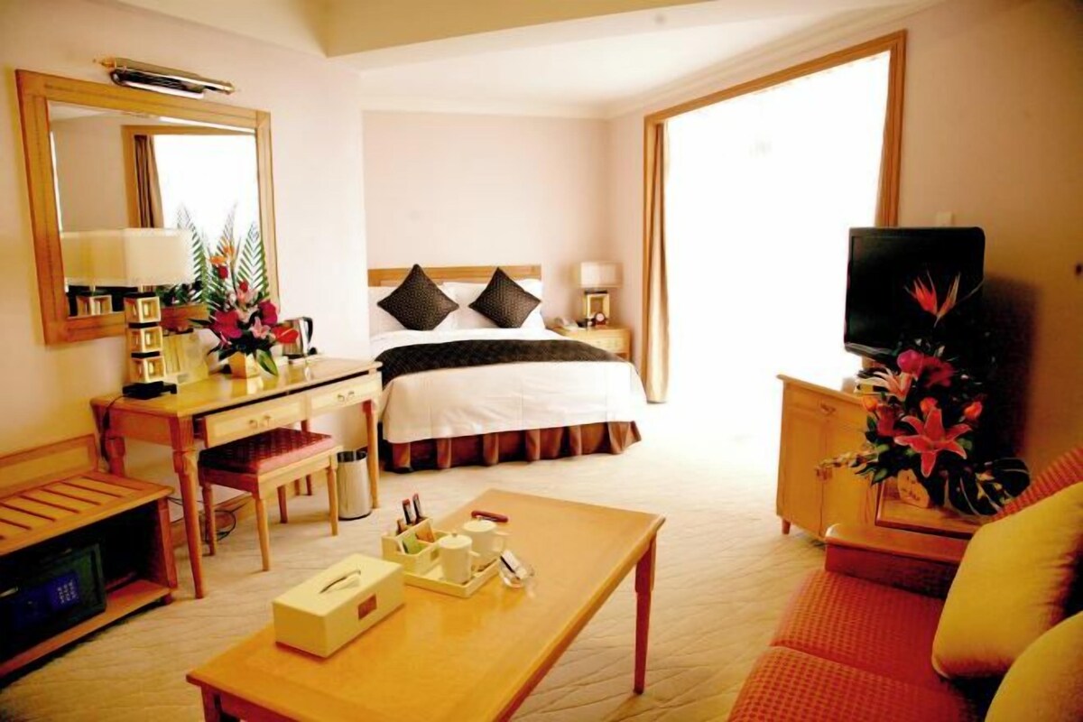 Una habitación de hotel con cama, escritorio, televisor y mesa de comedor.