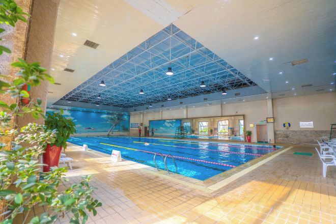 An indoor swimming pool with a high ceiling and a tiled floor.