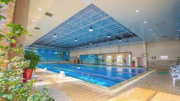 An indoor swimming pool with a high ceiling and a tiled floor.