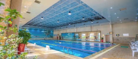 An indoor swimming pool with a high ceiling and a tiled floor.