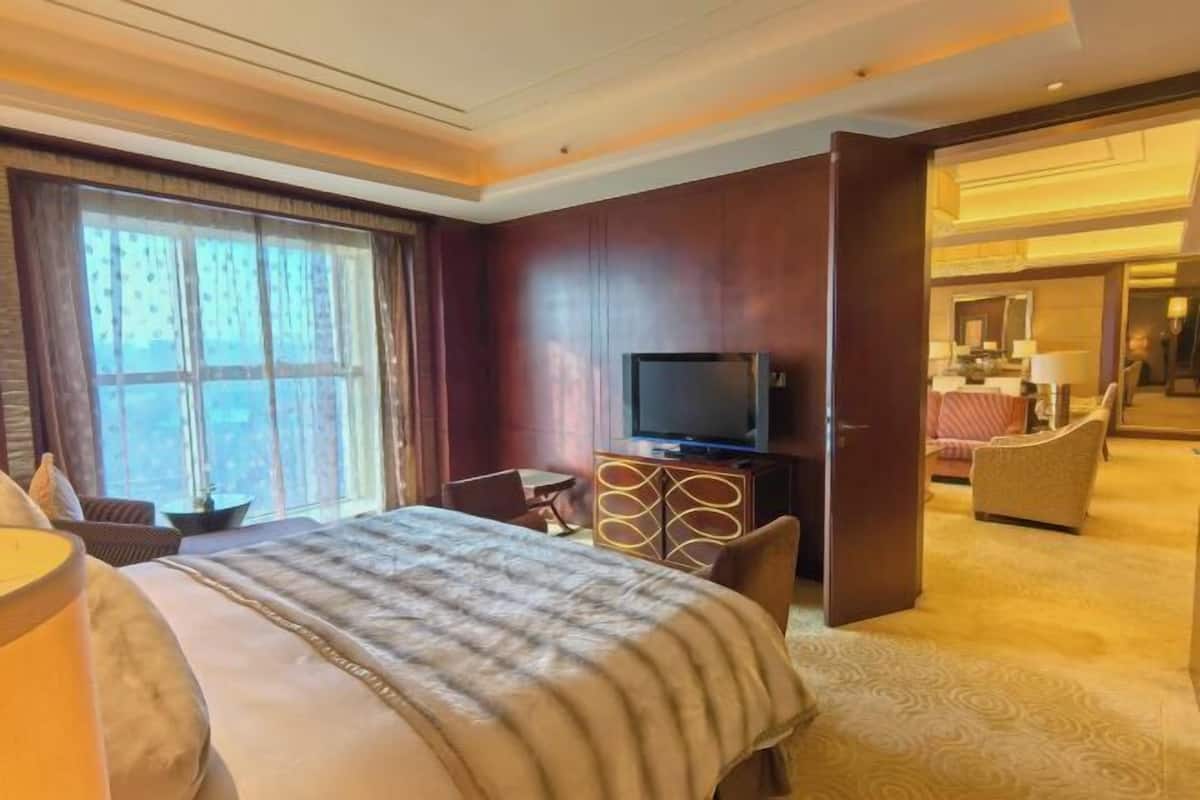 Ein Hotelzimmer mit einem Bett, einem Fernseher, einem Schreibtisch und einem Sessel.