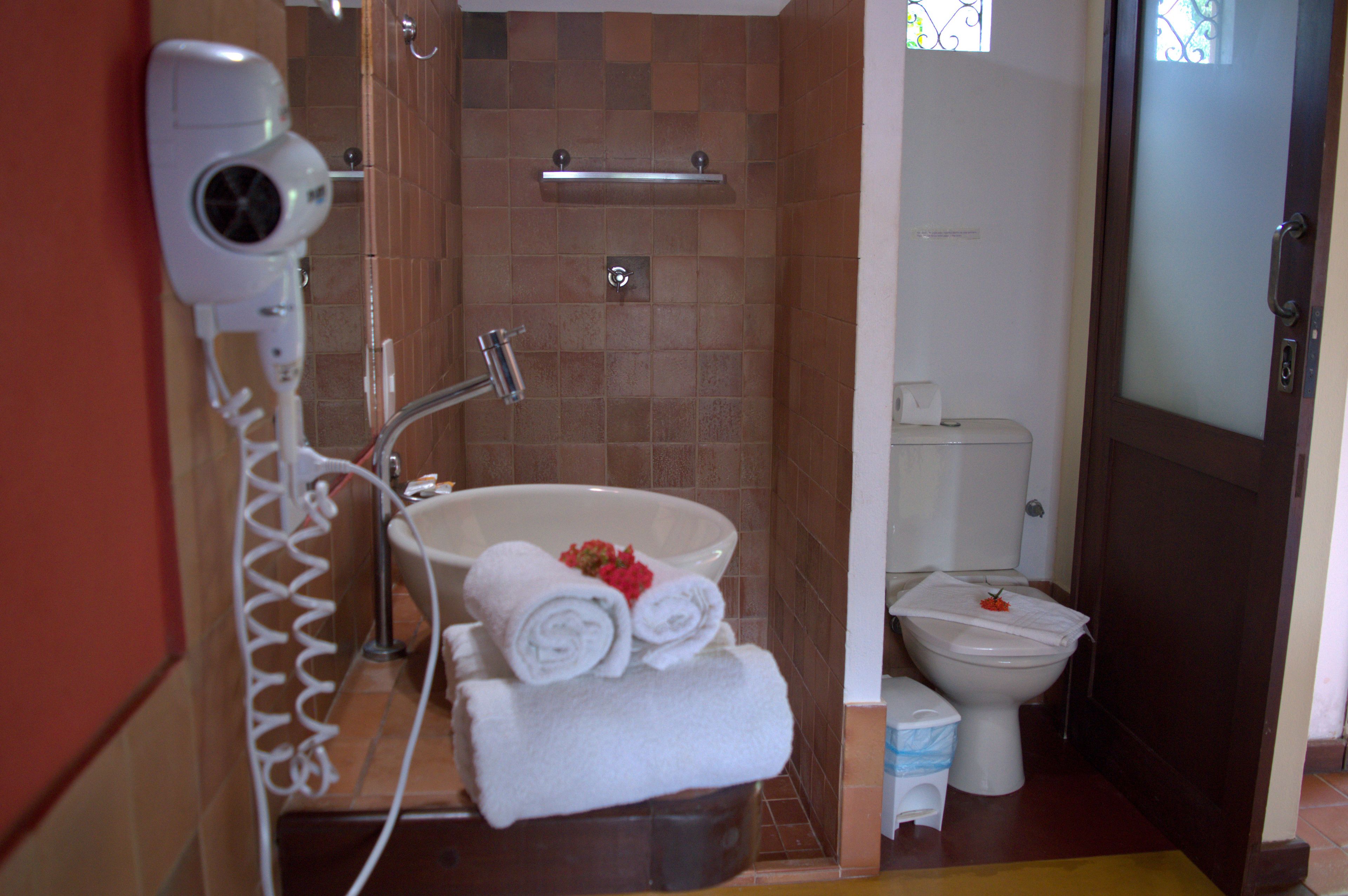 A bathroom with a shower, a sink, a toilet, and a hairdryer on the wall.