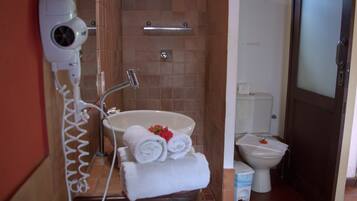 Une salle de bain équipée d’une douche, d’un lavabo, de toilettes et d’un sèche-cheveux fixé au mur.