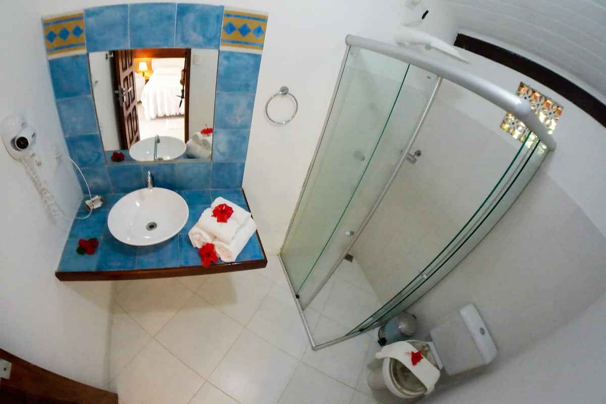 Un baño con un lavamanos redondo, un espejo y una cabina de ducha de vidrio.