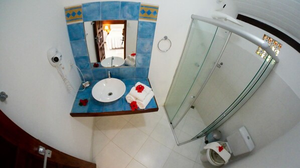 Un baño con un lavamanos redondo, un espejo y una cabina de ducha de vidrio.