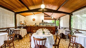 Un restaurante con mesas redondas y sillas de madera, suelo de piedra y techo de madera.