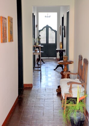 Un couloir doté d’un plancher en bois, d’une porte noire avec un cadre blanc et d’un lustre au plafond.